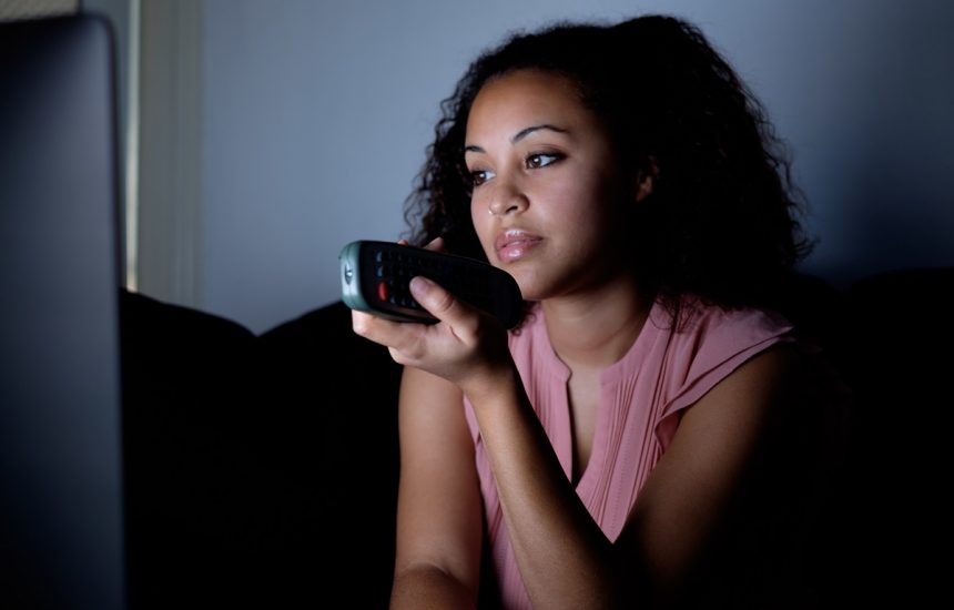 Bored woman holding television remote at night Watching Infomercial